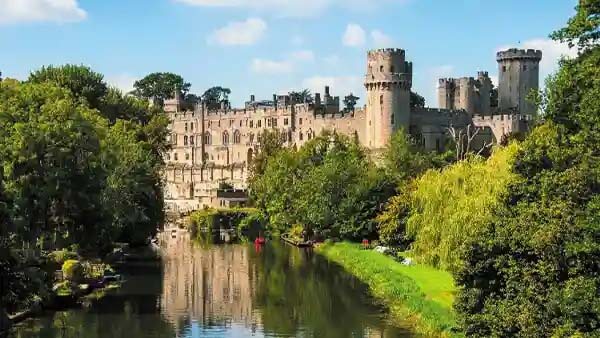 Scenic shot including warwick castle and the water up to the castle with the riverbank