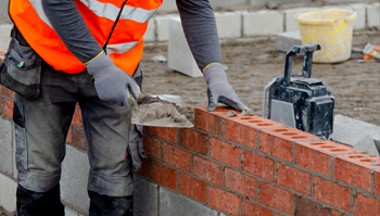 RecruitEasy Bricklayers Required shown with an image of a bricklayer laying a brick on mortar on a brown brick wall
